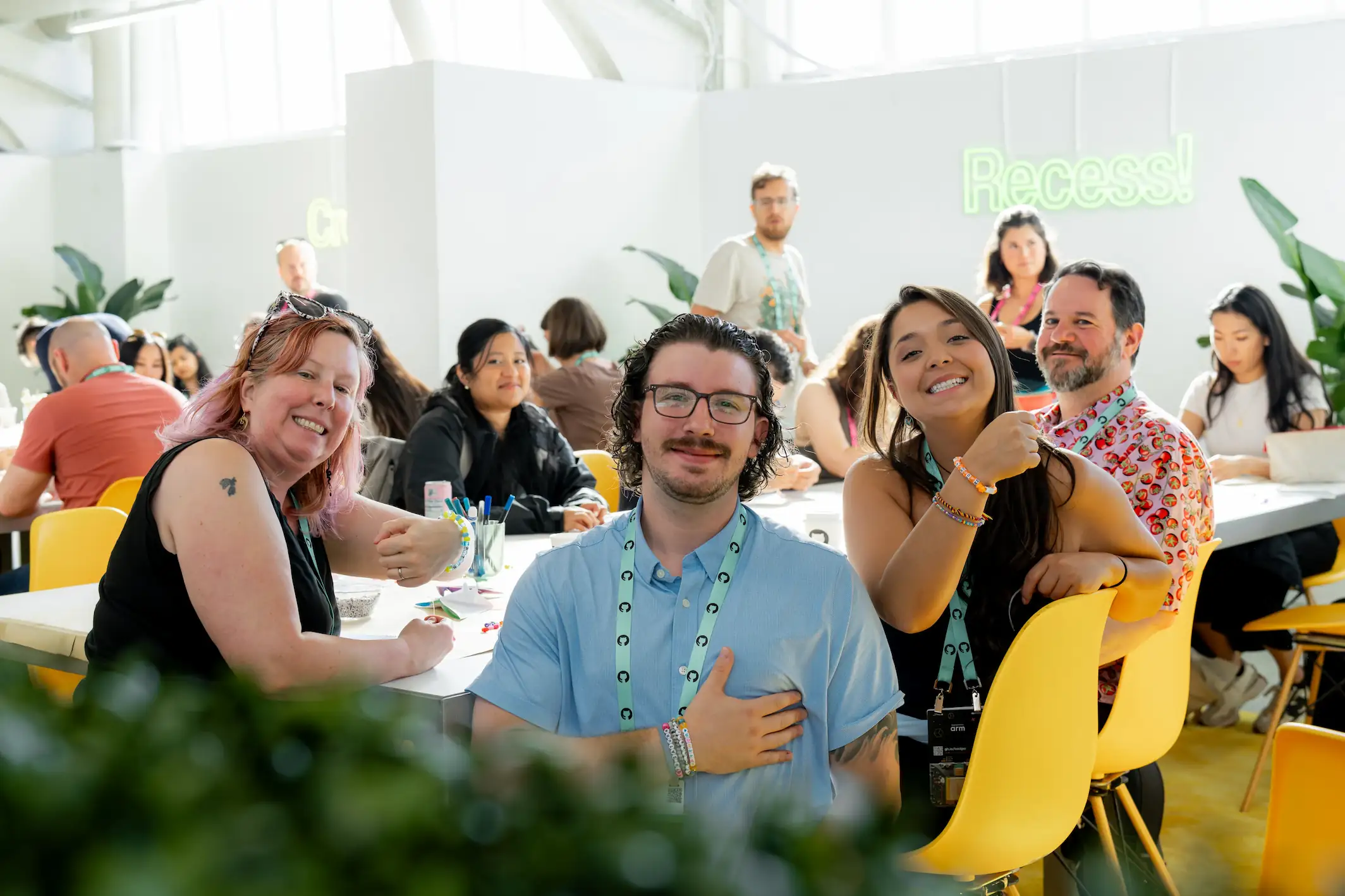 GitHub Universe attendees smile and gather around tables in a bright lounge area during a break.