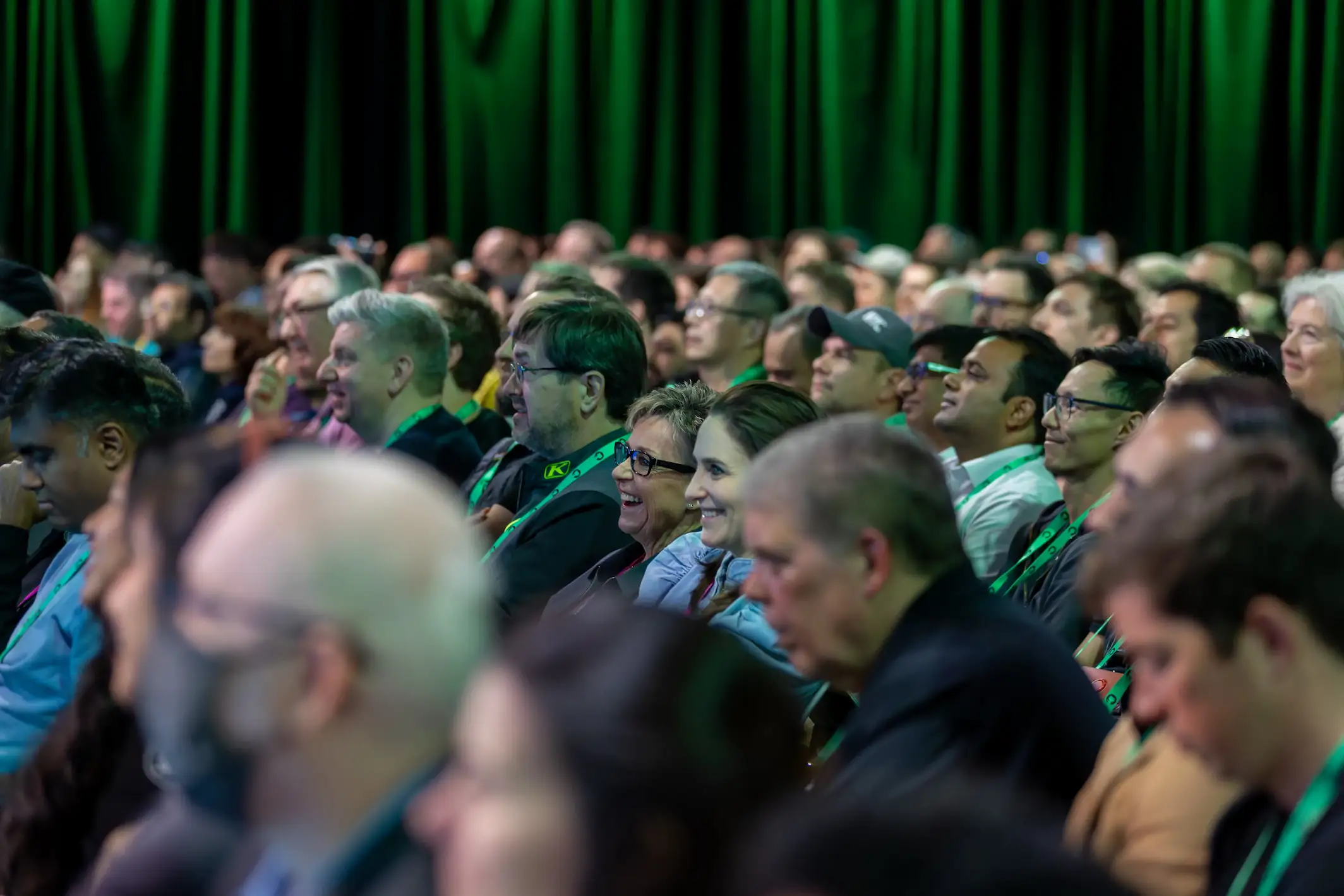 A large audience sits closely together and watches a GitHub Universe presentation.