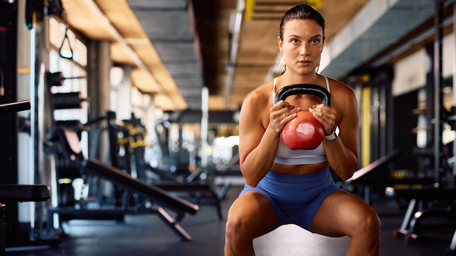 A woman doing a workout and squats using weights