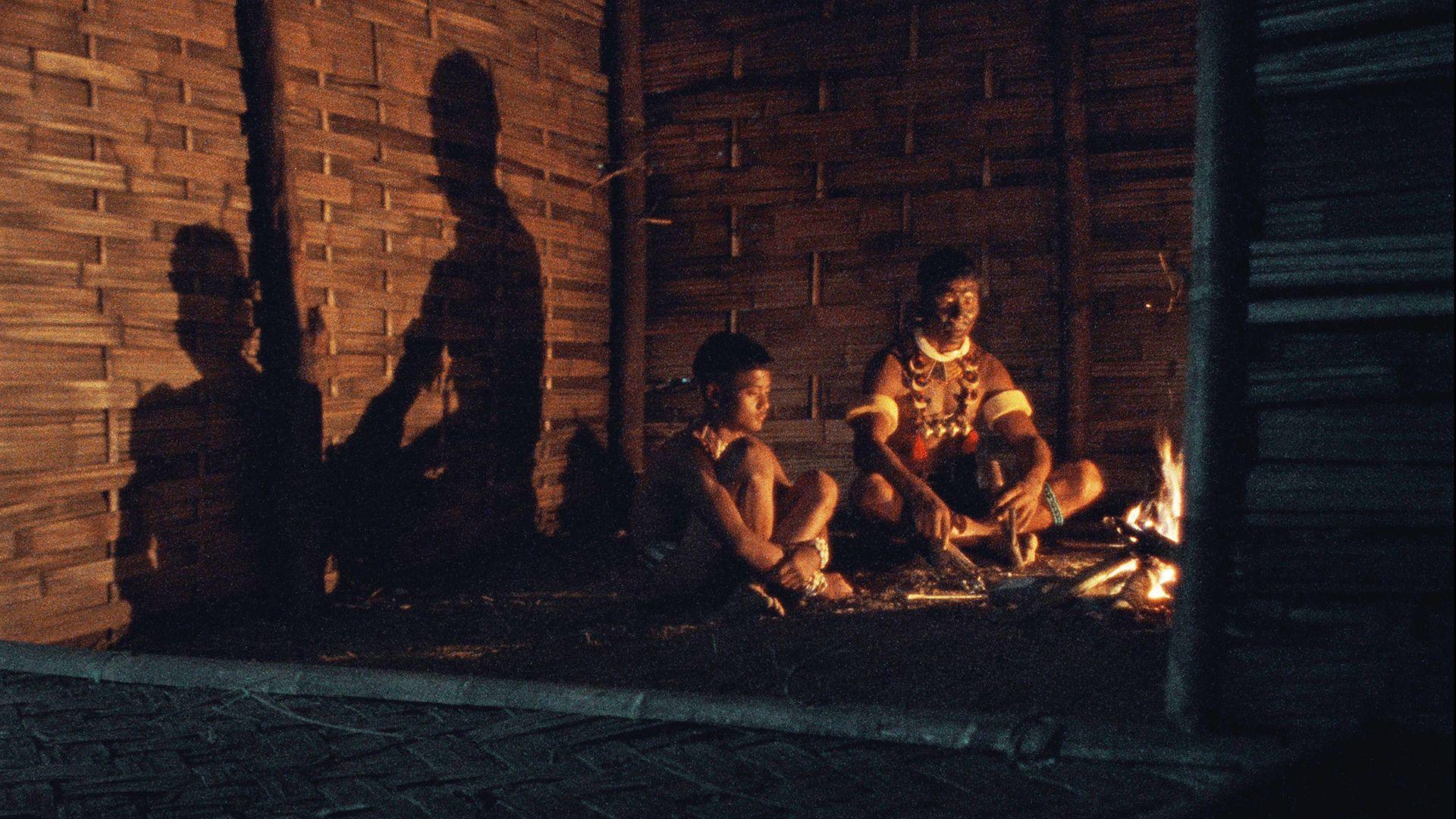 A still from the movie Angh where a man is sitting with his son in the dark 