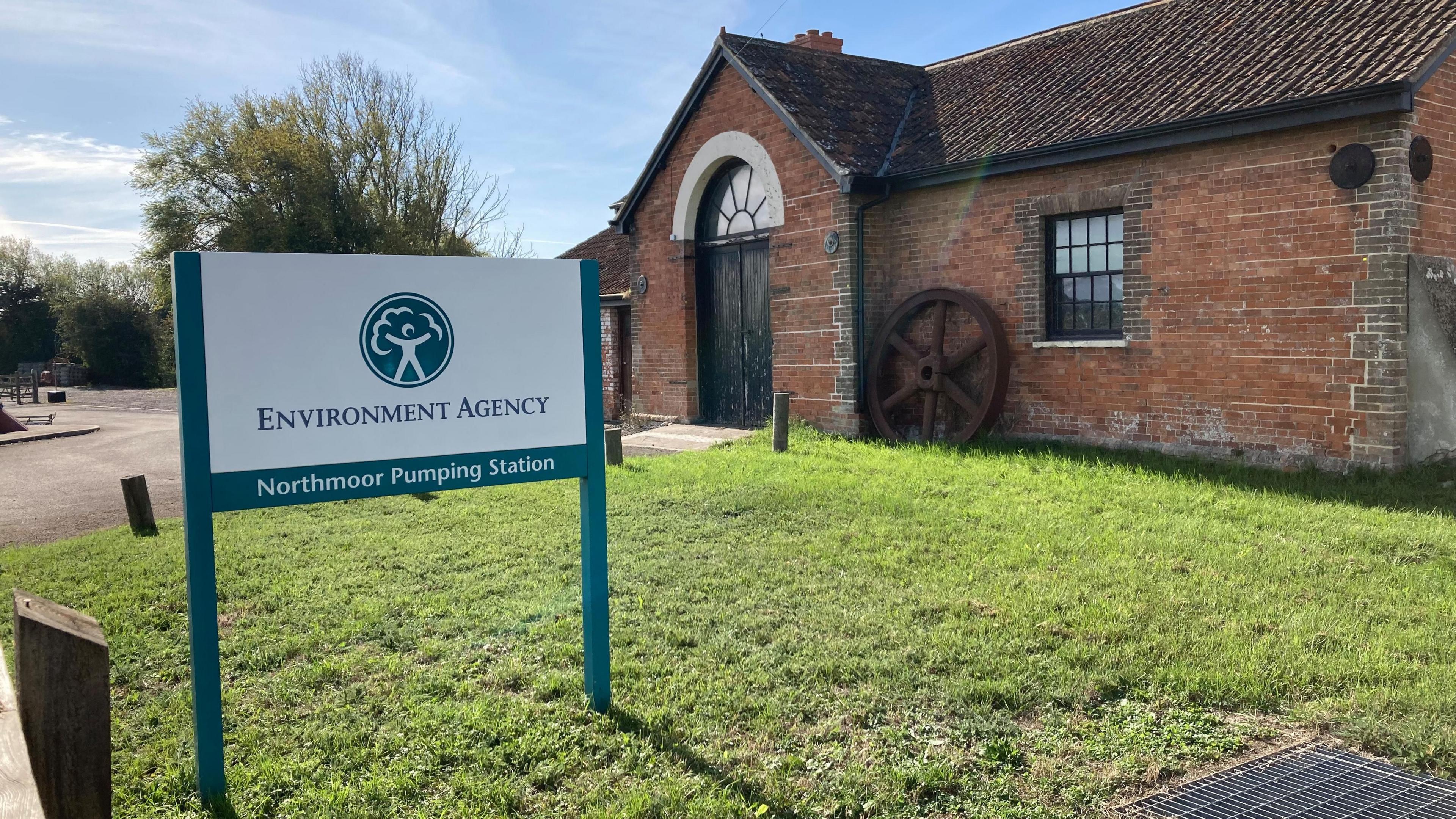 A view of Northmoor Pumping station with an Environment Agency sign in the front. The house behind the sign is built of red bricks.
