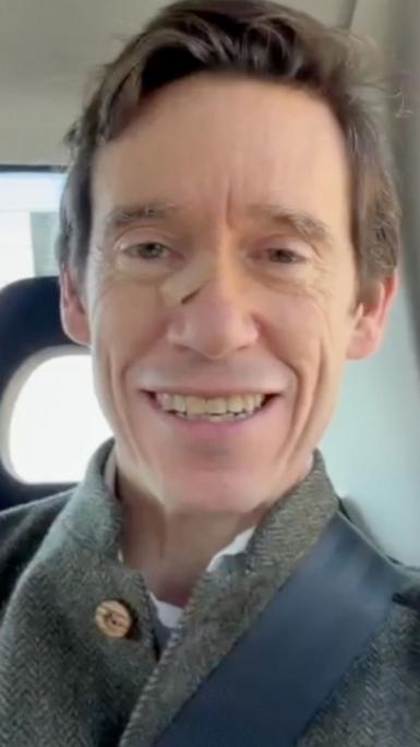 Rory Stewart is smiling at the camera. He is in a car and wearing a seatbelt. Only his face and shoulders are visible.
