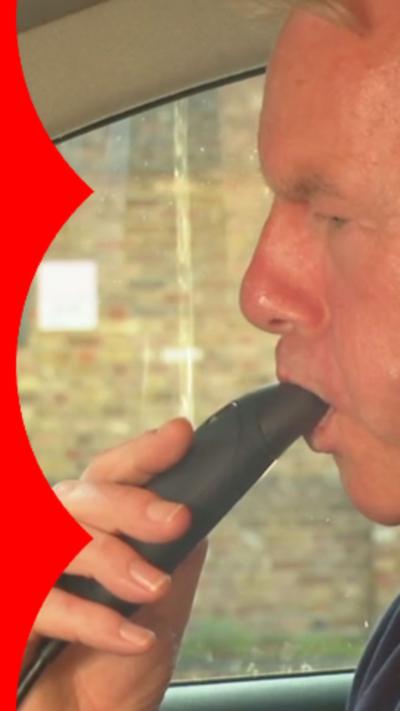A man blowing into a device set inside a car
