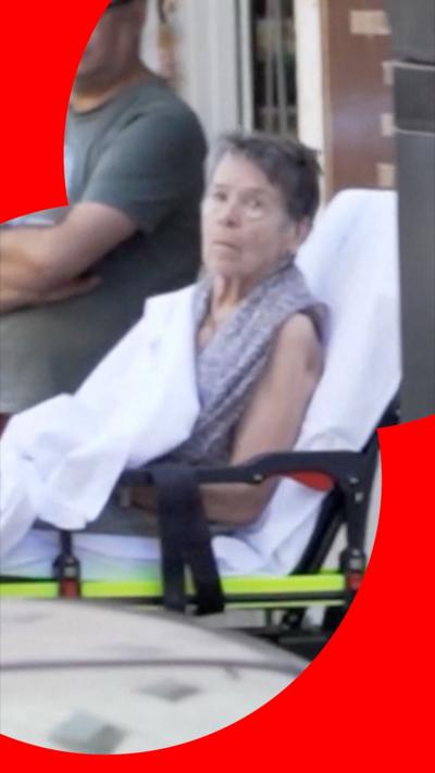 An 87-year-old woman on a wheeled stretcher on the street.