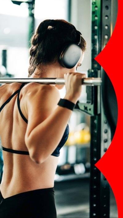 Rear view of a woman in a black strappy top lifting heavy weights.