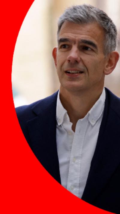 BBC Director General wearing a dark coat over a white shirt. He has short grey hair.