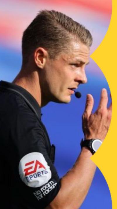 Dan Robathan has short blonde hair and is wearing a referee kit. He has a whistle in his mouth.