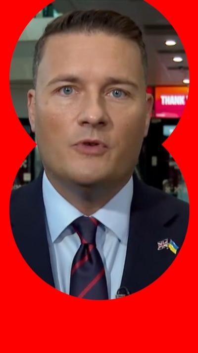 Defence Secretary Wes Streeting looks directly into the camera. He has short dark hair. He is is wearing a white shirt, a navy blue tie with narrow red diagonal stripes and a navy suit jacket.