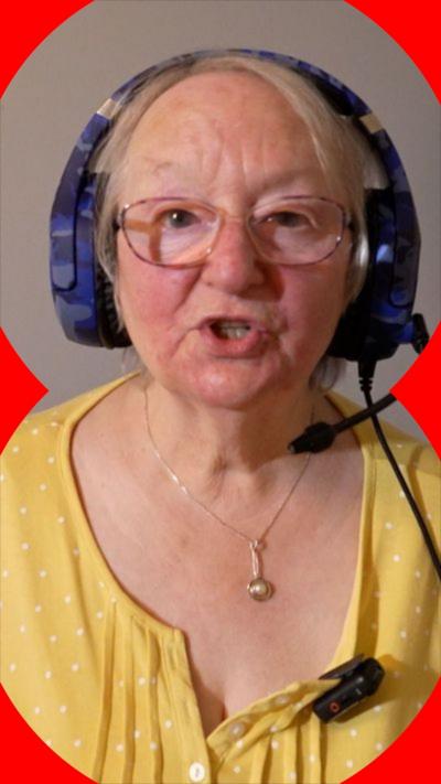 A woman wearing a purple headset and a yellow blouse talks to the camera