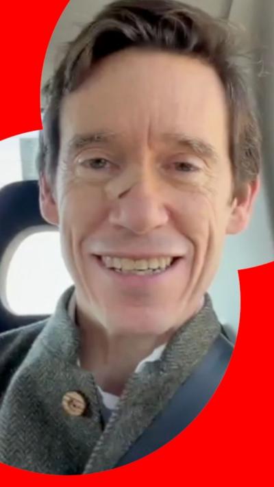 Rory Stewart is smiling at the camera. He is in a car and wearing a seatbelt. Only his face and shoulders are visible.