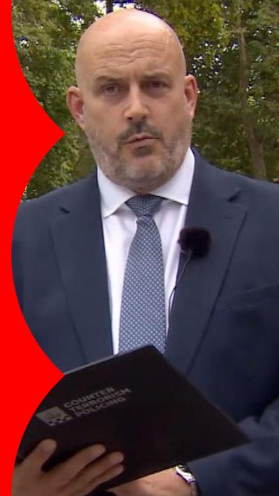 Laurence Taylor wearing a navy blue suit and holding a folder