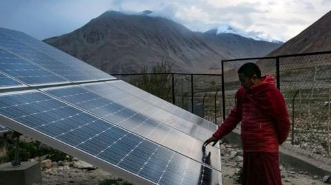 A monk touches solar panels at the Shachukul Monastery in the Ladakh region