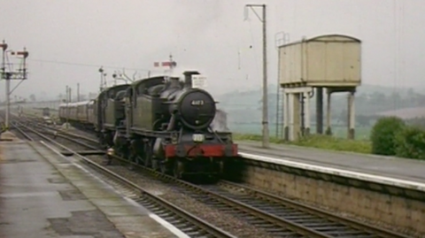 An archive image of an old train pulling into a station during a time when the railway line was active.