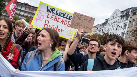 Germany students hold up several banners as they take part in a protest. 