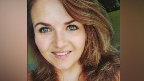 A closeup  of a woman with brown hair smiling at the camera. 