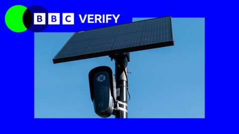 A black Flock surveillance camera attached to a pole with a solar panel attached above it