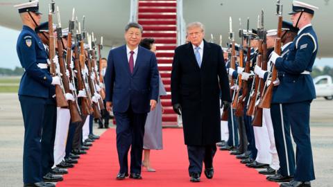 Donald Trump and President Xi on a red carpet flanked by guards in military uniform holding guns