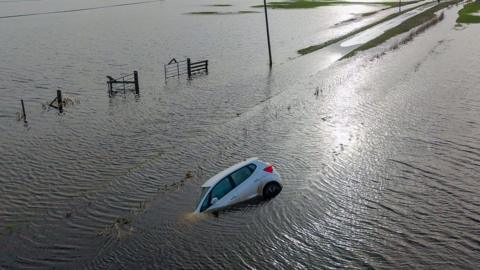 Car on its side lying in waterlogged field