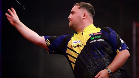 Luke Littler throws a dart during a competition