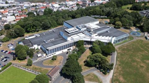 A picture taken from above looking down at Beau Sejour leisure centre. There is a number of buildings and fields surrounding it