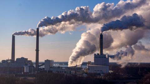 Smoke billows from power plant chimneys.