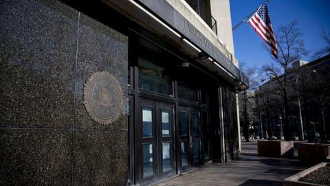 Close-up of the entrance of the FBI headquarters, with the US flag flying above it, in Washington DC