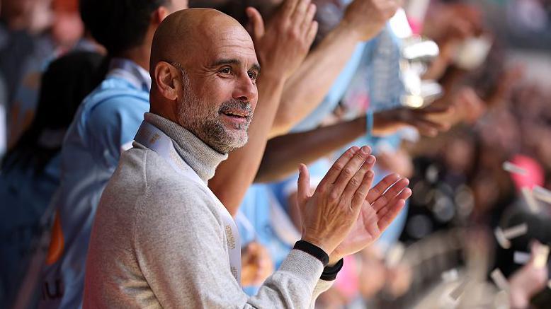 Manager Pep Guardiola applauds as his Manchester City players lift the FA Cup trophy after beating Chelsea in the 2026 final