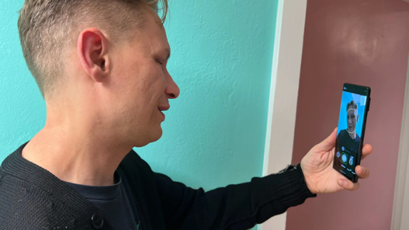 A person holds a smartphone using a guided frame feature to take a selfie.
