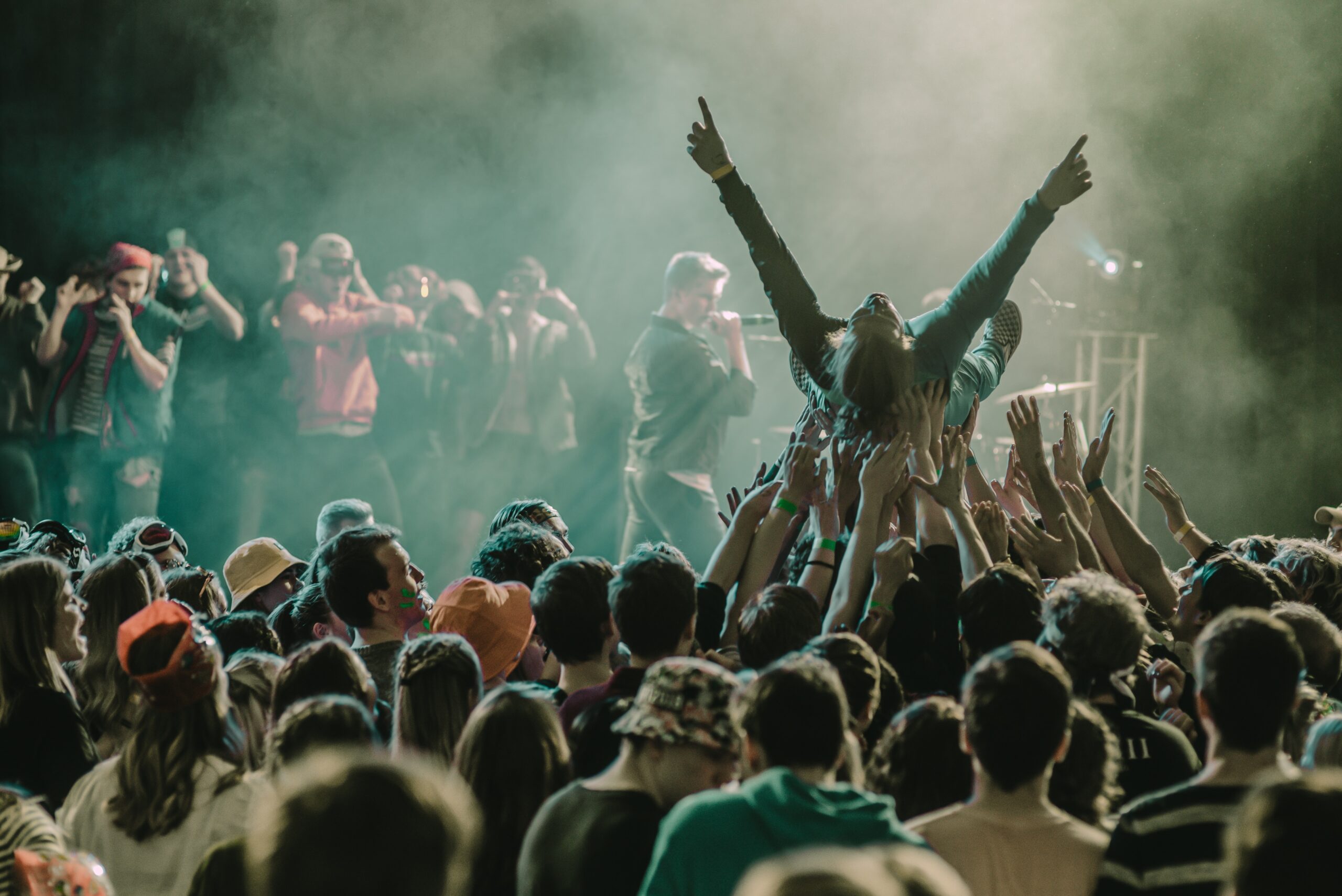 Fani yleisön kannettavana "crowd surffaamassa". Artisti taustalla lavalla vetämässä keikkaa.