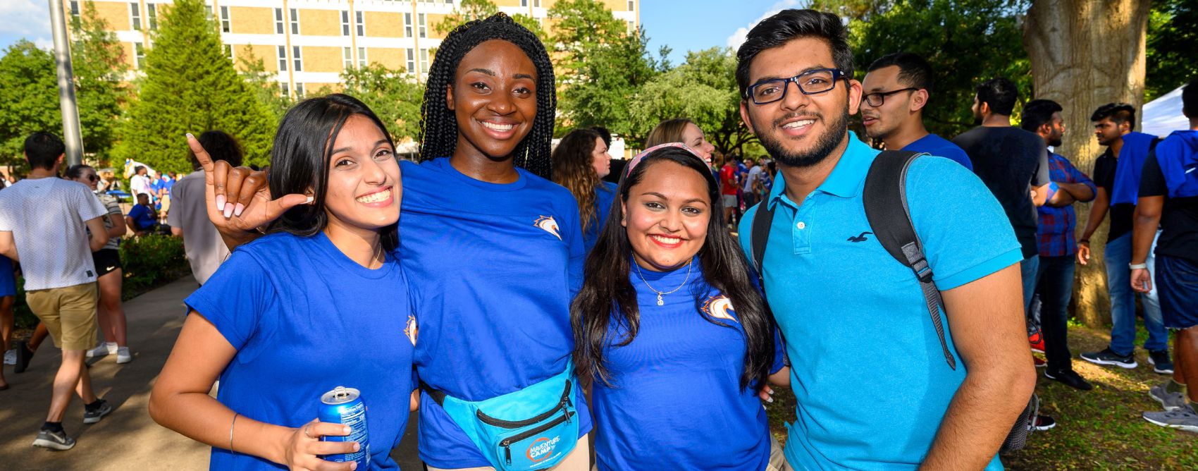 four students happily standing shoulder to shoulder